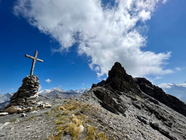 Gipfel mit Gipfelkreuz bei blauem Himmel und einer kleinen Wolke