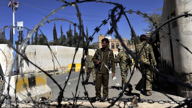 Bewaffnete Kämpfer hinter Stacheldraht bewachen die Regierungsgebäude in Sanaa.