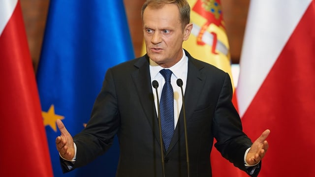 Donald Tusk vor Flaggen.