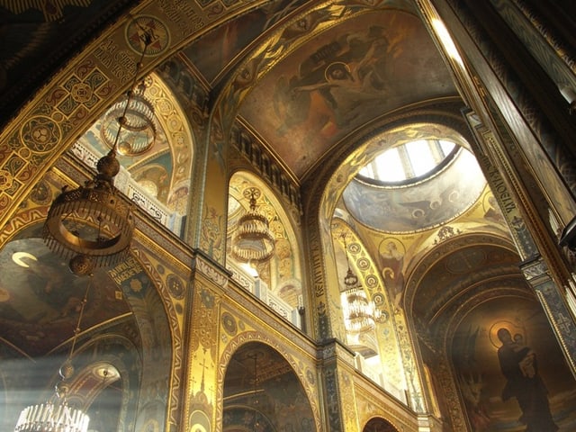 Innenansicht einer vergoldeten orthodoxen Kirche mit religiösen Fresken.