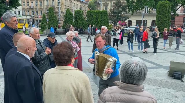 Eine Gruppe von älteren Personen singt Volkslieder auf der Strasse.