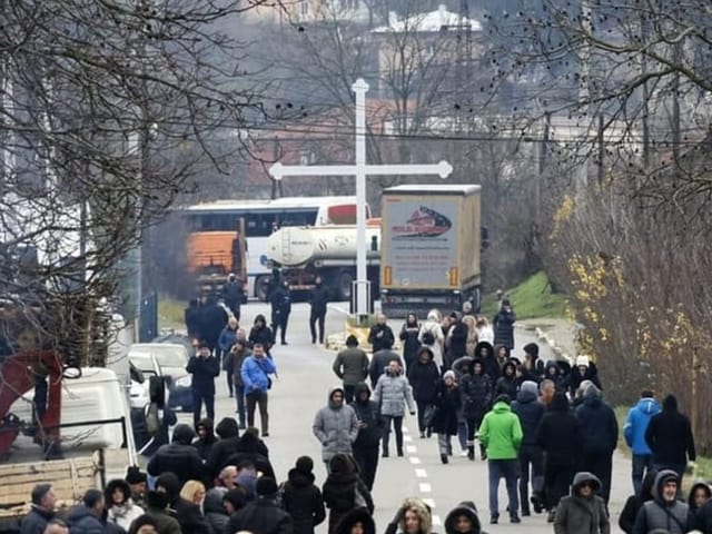 Menschen auf von Lastwagen blockierter Strasse