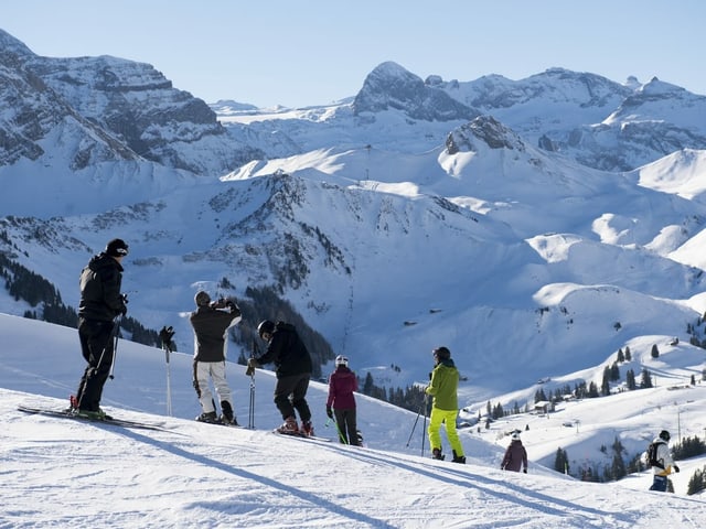 Einige Skifahrer stehen am Pistenrand.