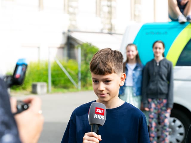 Lenny (12) wird gefilmt und hält das Mikrofon in der Hand.