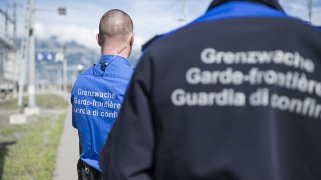 Zwei Grenzwächter stehen an einem Bahnhof.