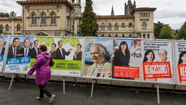 Eine Frau geht vor Wahlplakaten durch.