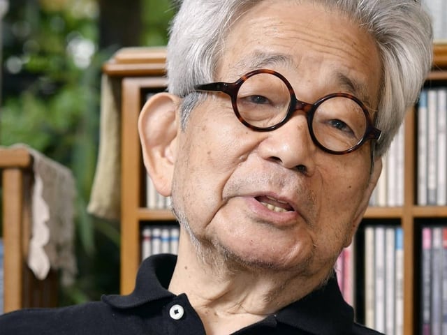 Ein Foto von Kenzaburo Oe vor Bücherregal.