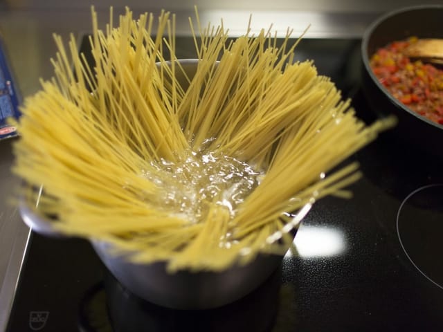 Rohe Spaghetti werden in einer Pfanne gekocht