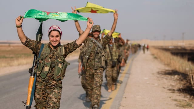 Kurdische Kämpfer posieren mit der Flagge ihrer Partei in Tel Abjad. 