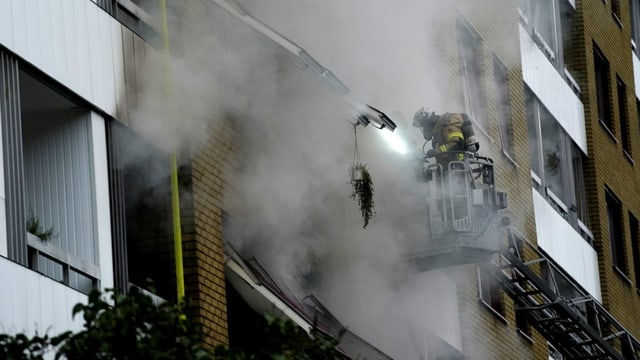 Einsatzkräfte evakuieren Menschen aus dem brennenden Wohnblock.