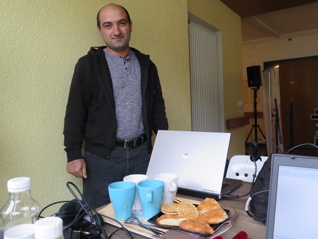 Mann mit Tablett, auf dem Kuchenstücke und Tassen stehen