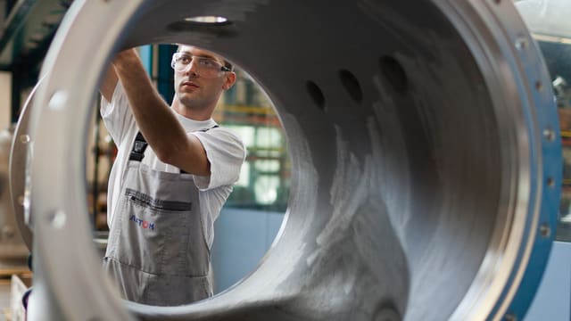 Arbeiter durch ein Metallrohr fotografiert, an dem er etwas montiert