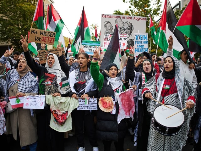 Frauen mit Palästinensertüchern bei einer Demonstration in Berlin.mit Schildern und palästinensischen Flaggen.