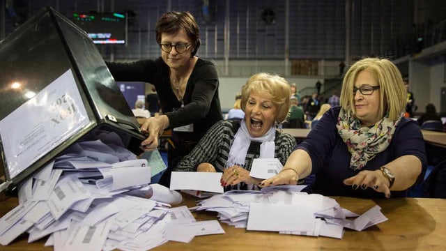 Frauen nehmen die Wahlzettel entgegen.