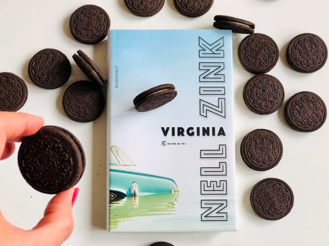 Annette König hält einen Oreo in der Hand. Dahinter sieht man Nell Zinks neuen Roman «Virginia»