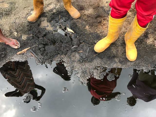 Die Silhouetten der Bauern Gberebia Biraalo und Barisitom Keenom spiegeln sich im ausgelaufenen Rohöl.