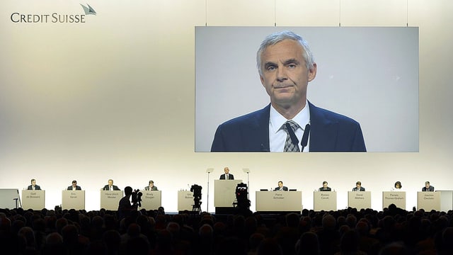 CS-Führung an der Generalversammlung der Bank. Gross auf einem Bildschirm zu sehen ist CS-Präsident Urs Rohner.