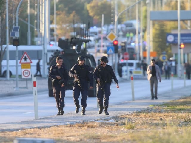 Drei Polizisten auf Strasse mit Einsatzfahrzeug im Hintergrund.