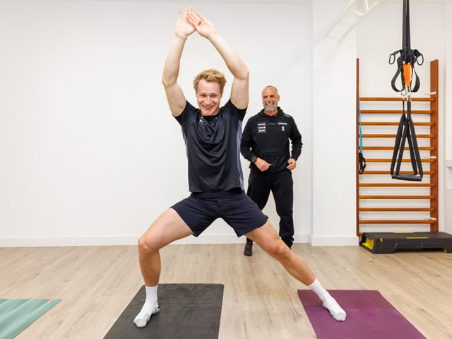 Mann macht Fitnessübung mit Trainer im Raum.