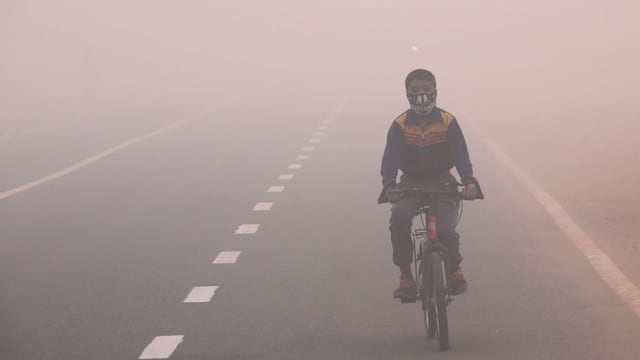 Kind mit Atemmaske auf dem Fahrrad