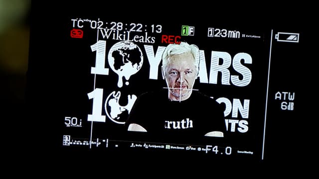 Julian Assange auf einem Foto von der Leinwand. Er trägt ein T-Shirt mit der Aufschrift «truth».