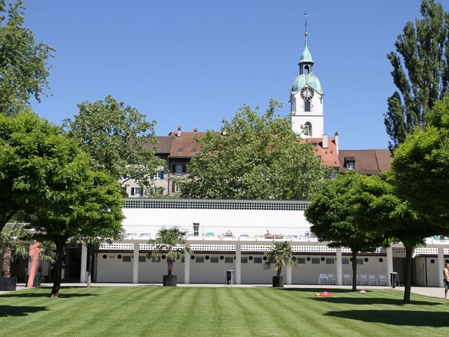 Freibad von Olten mit Rasenfläche im Vordergrund und Kirche im Hintergrund. 