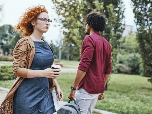 Eine junge Frau und ein junger Mann gehen aneinander vorüber, scheinbar ohne sich zu bemerken