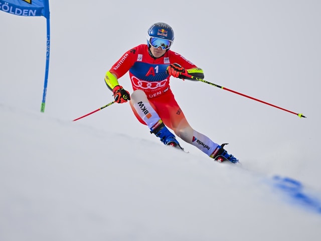 Skifahrer in rotem Anzug bei einem Riesenslalomrennen.