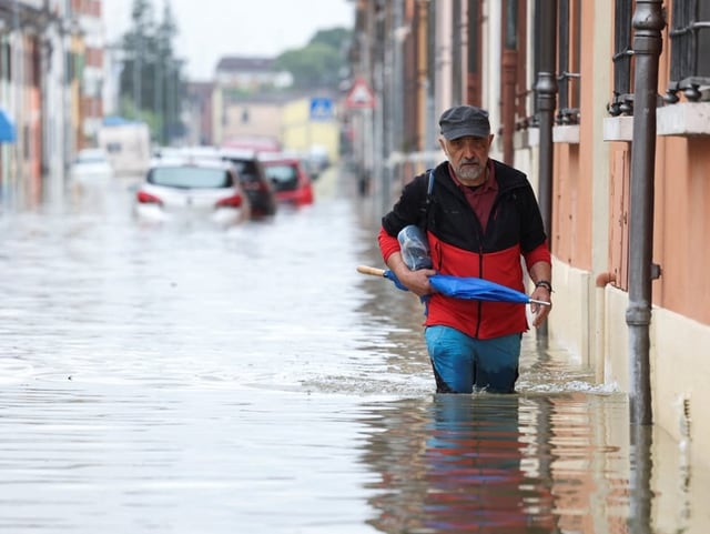 Ein Mann watet nach schweren Regenfällen in der Region Emilia-Romagna durch Hochwasser. 