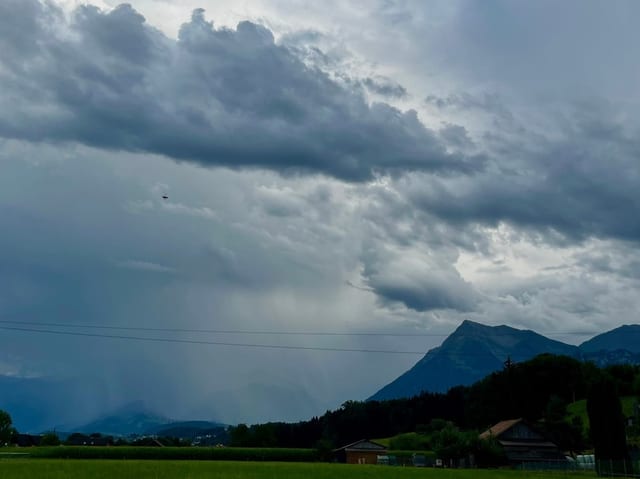 Blick auf eine ländliche Landschaft mit Bergen und bedrohlichen Wolken.