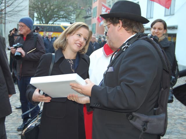 Christa Markwalder erhält ein Paket von einem Mann.