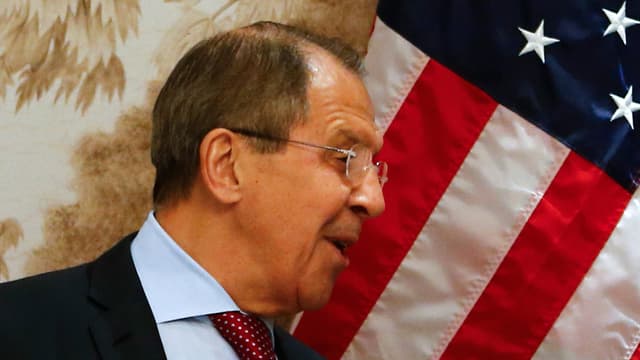 Russlands Aussenminister Sergej Lawrow schmunzelt vor einer US-Flagge.