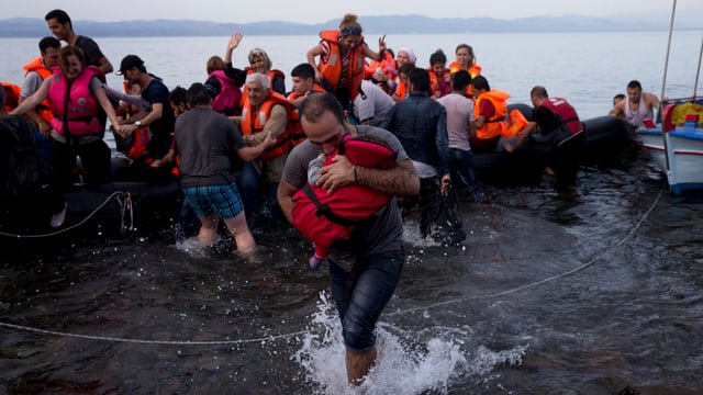 Ankunft auf der Insel Lesbos. Ein Vater hält sein Kind fest an sich gedrückt.