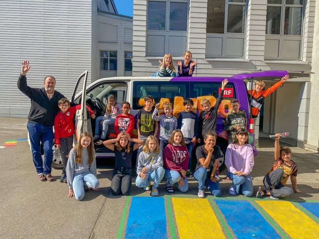 Kinder stehen vor dem Zambo-Bus und winken in die Kamera.