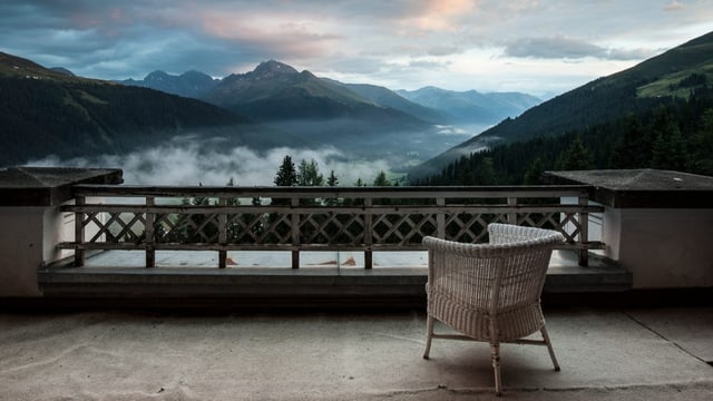 Ein Stuhl auf einer Terrasse, schöner Ausblick in das Tal mit Nebelschwaden