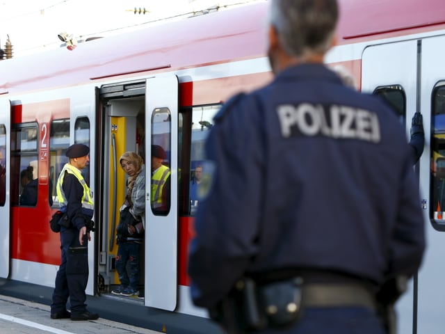 Flüchtlinge, begleitet von der Polizei, stehen im Zugwagon bereit zur Abfahrt. 