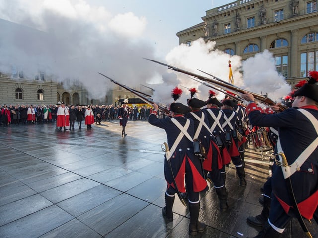 Die Ehrenformation feuert Salutschüsse in den Berner Himmel über dem Bundesplatz. 