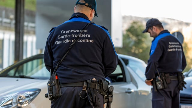 Grenzwächter kontrollieren ein Auto.