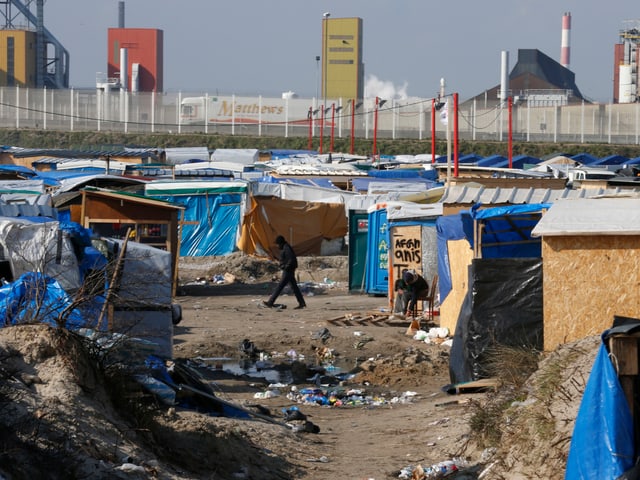 Zelte und Bretterverschläge auf offenem Gelände.