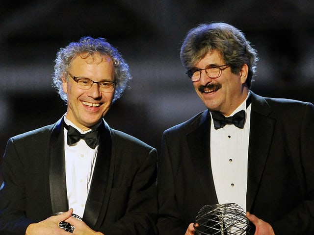 Zwei Männer in Smoking mit Trophäen.