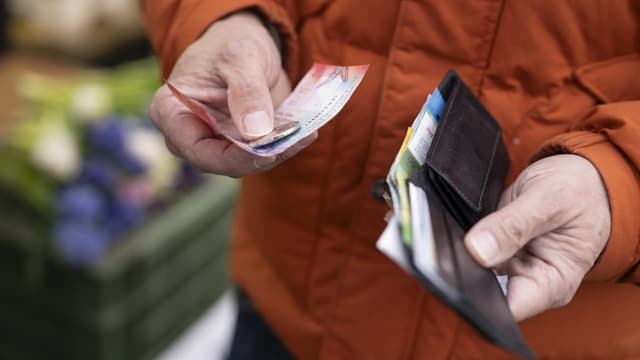 Mann hält in einer Hand sein Portemonnaie und in der anderen Geld