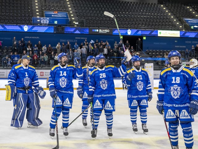 Eishockeyspieler in blauen Trikots auf dem Eis nach dem Spiel.