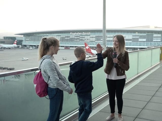 Anna klatscht mit Jamin ab auf der Flughafenzuschauerterrasse.