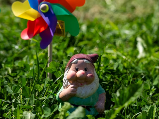 Ein kleiner Gartenzwerd mit einem Windrad im Gras