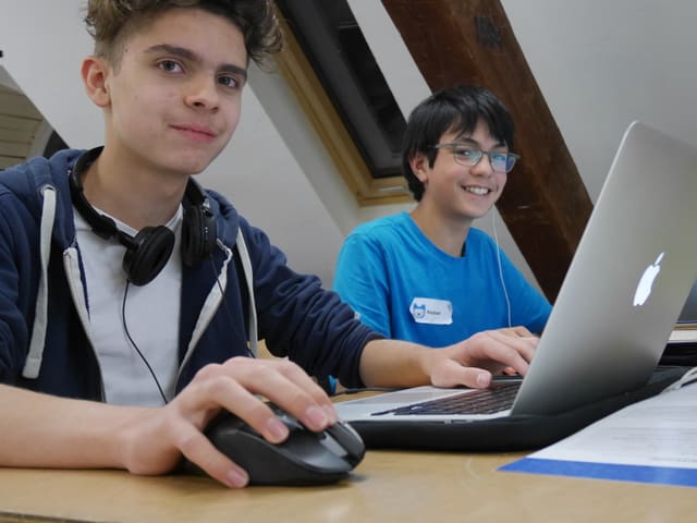 Zwei Jungen sitzen for einem Computer.