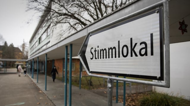 Wegweiser mit der Aufschrift «Stimmlokal» vor einem Gebäude