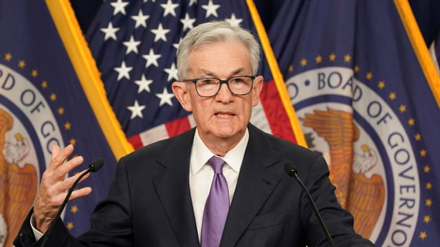 Jerome Powell, hinter ihm Flaggen.