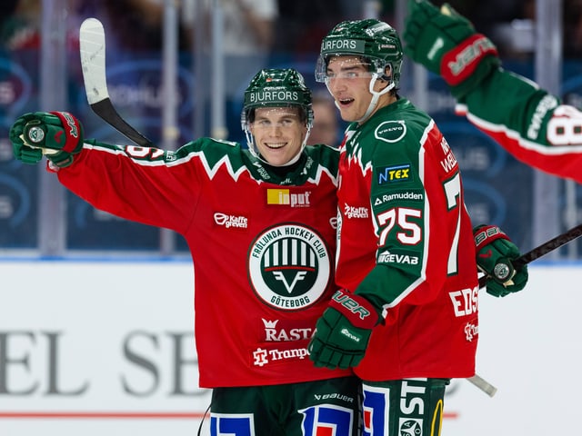 Zwei Eishockeyspieler in roten Trikots auf dem Eis.