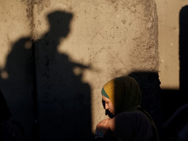 Palästinenserin in der Altstadt von Jerusalem, dahinter der Schatten eines Soldaten. 