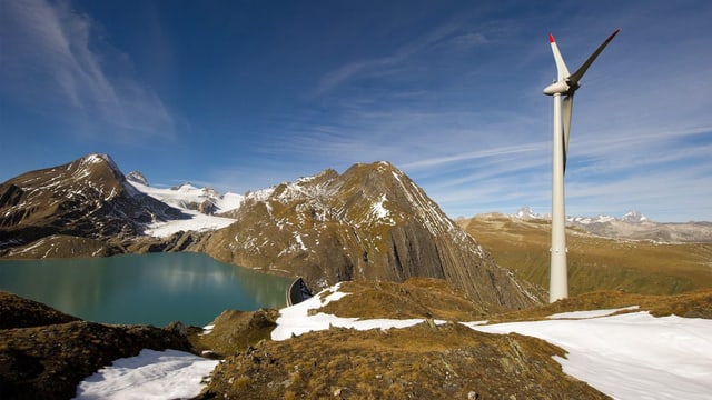 Windturbine in den Bergen. Dahinter Stausee